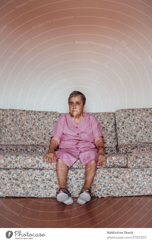 Senior woman sitting alone on the sofa at home old loneliness indoors alzheimer mental health one person retirement memory aged home interior grandmother senior