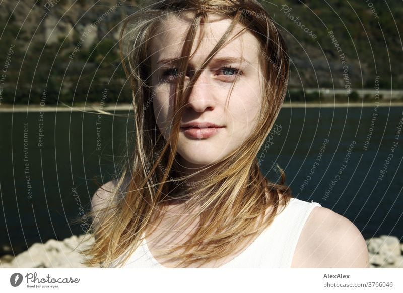 Close portrait of a young woman with wind-blown hair in a white dress in front of the Rhine bank Woman Young woman Slim already athletic Blonde youthful