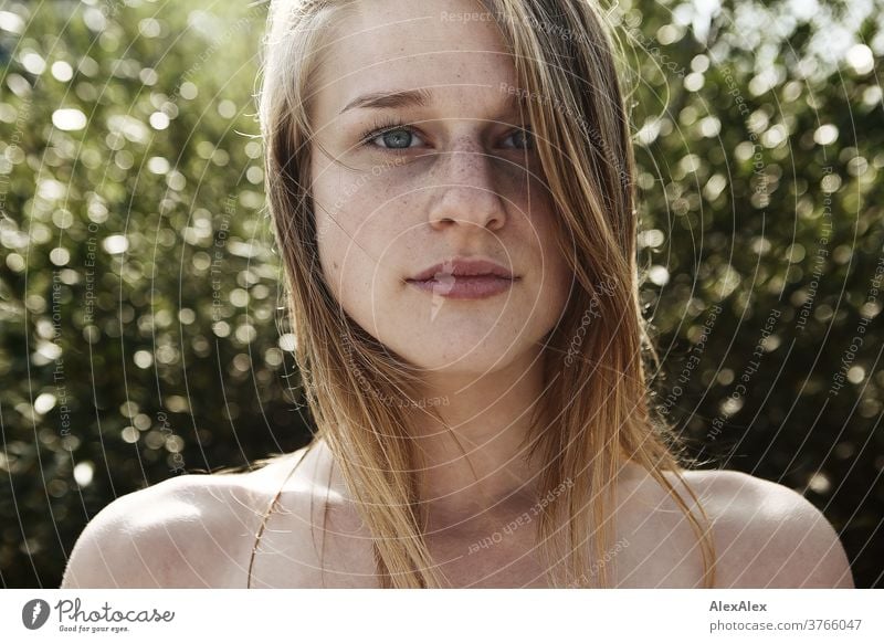 Close up backlight portrait of a young, freckled woman with wind-blown hair in front of a bush Woman Young woman Slim already athletic Blonde youthful