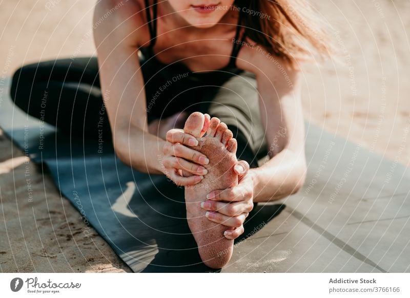 Anonymous woman doing yoga in Head to Knee pose forward bend flexible stretch mat relax janu sirsasana female position beach healthy summer fit tranquil