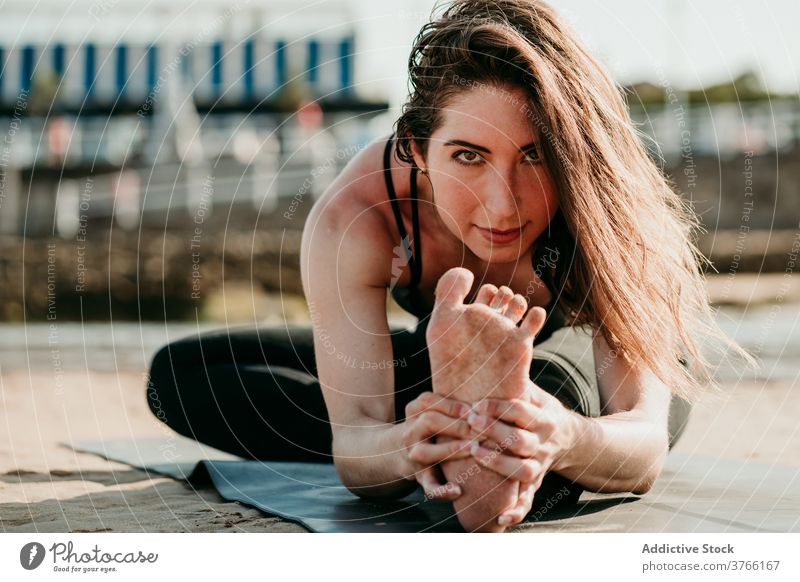 Content woman doing yoga in Head to Knee pose forward bend head to knee pose flexible stretch mat relax janu sirsasana female position beach healthy summer