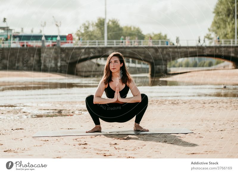 Slim woman in Garland pose doing yoga on beach garland pose malasana practice balance summer female shore mat tranquil river healthy slim harmony peaceful