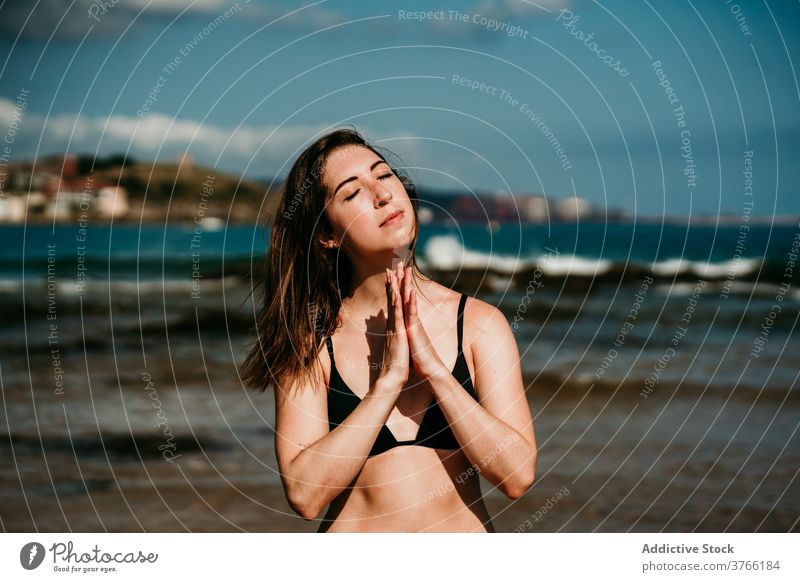 Slender woman doing yoga on the beach asana practice slim tranquil seashore bikini female seascape wellness peaceful zen posture nature wellbeing spirit