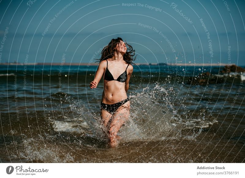 Carefree woman running in sea water having fun splash summer vacation holiday bikini female shallow resort relax carefree happy smile nature rest young delight