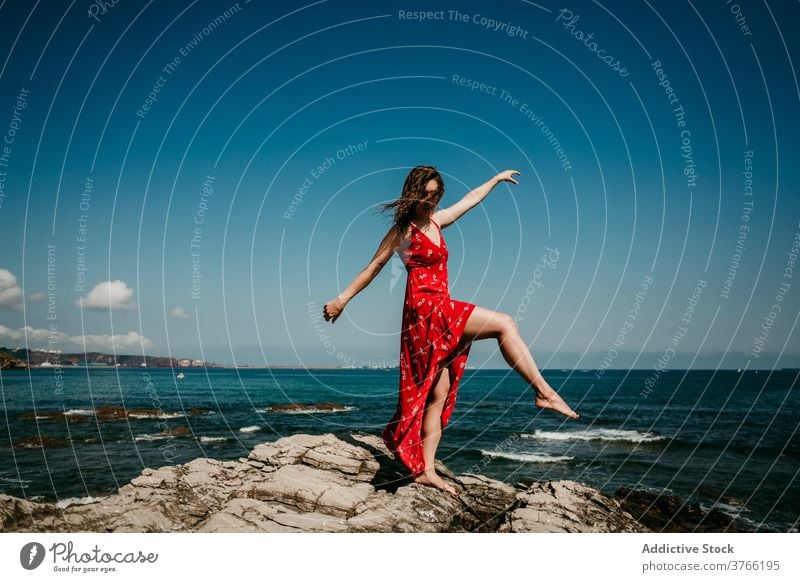 Graceful woman in dress on rocky hill grace red balance tender delight move slim female barefoot rough blue sky cloudless heaven nature serene sensual freedom