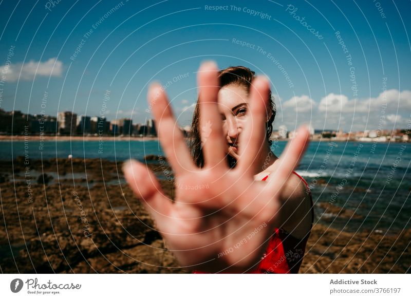 Smiling woman showing hands to camera grace reach out gesture seashore charming content demonstrate female sunny summer holiday coast beach happy stand pleasure