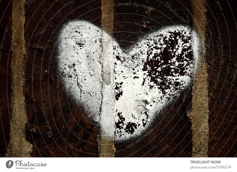 Dark brown bricks, connected with grey mortar joints, have been painted by someone with a big white heart, the colour of which has already chipped off in places