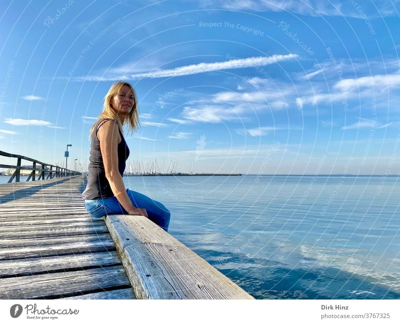 Blonde woman sitting on a pier on the Baltic Sea coast Woman 45 - 60 years already portrait Staring Looking Human being Adults Feminine Looking into the camera