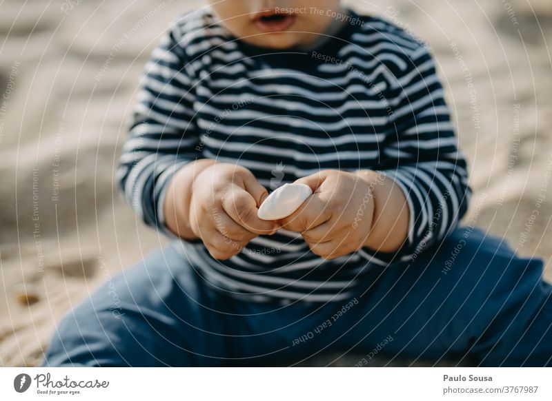 Toddler playing with sea Shell on the Sandy beach Sea mussel sea shell Beach Beach vacation Beach dune travel Caucasian Curiosity Vacation & Travel Mussel shell