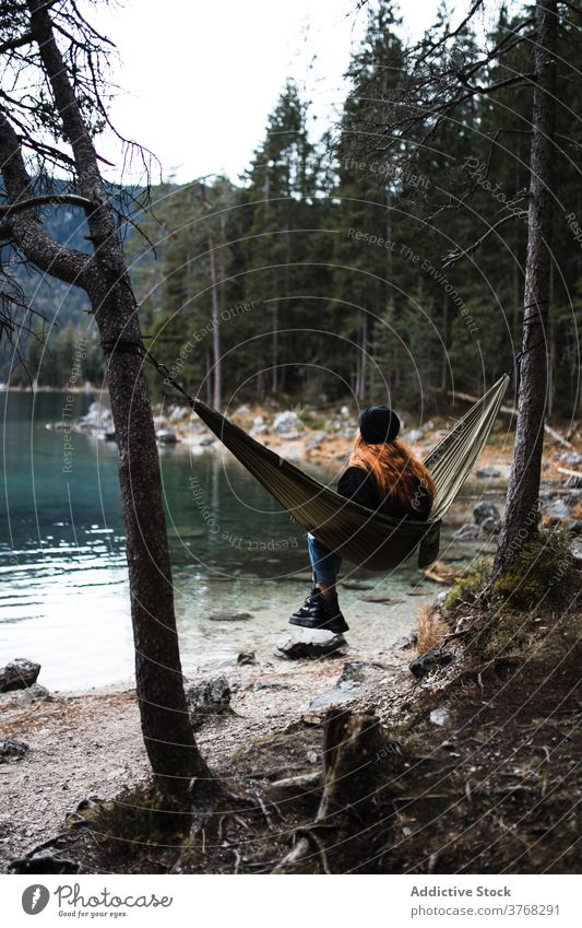 Woman relaxing in hammock near lake woman mountain admire scenery pond highland autumn female germany austria majestic nature traveler serene tourism peaceful