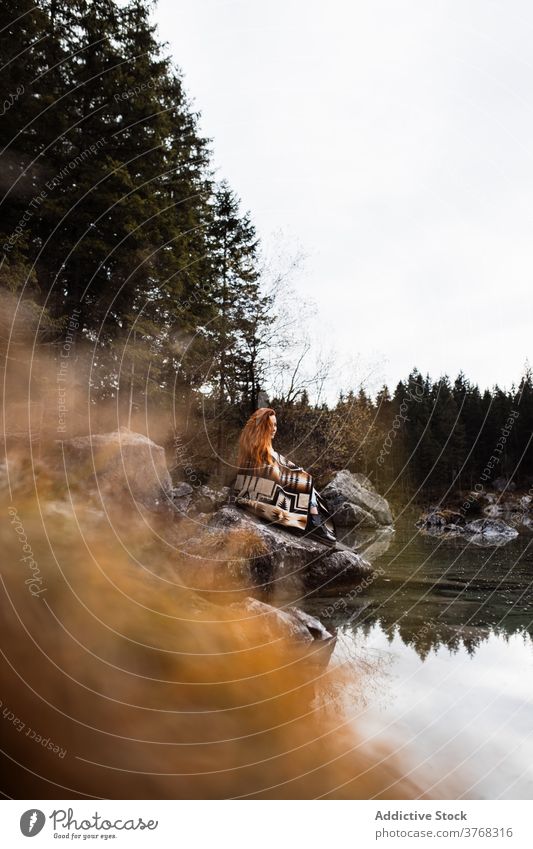 Woman sitting on stone on lake shore woman autumn alone gloomy contemplate silent tranquil female travel tourism germany austria nature water calm relax serene