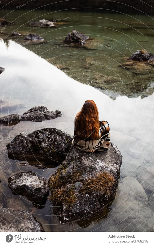 Woman sitting on stone on lake shore woman autumn alone gloomy contemplate silent tranquil female travel tourism germany austria nature water calm relax serene