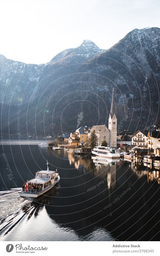 Coastal town on rocky shore of fjord with floating boat mountain coast lake church settlement house landscape countryside nature water ridge range village