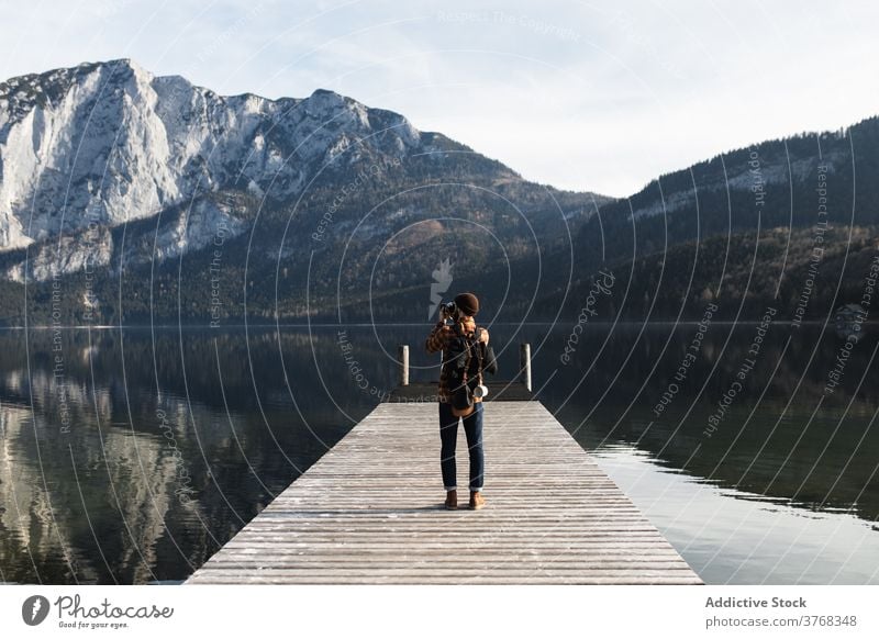 Traveler taking picture of mountains from pier near lake man take photo boardwalk autumn rock shore photographer adventure coast nature male travel tourism