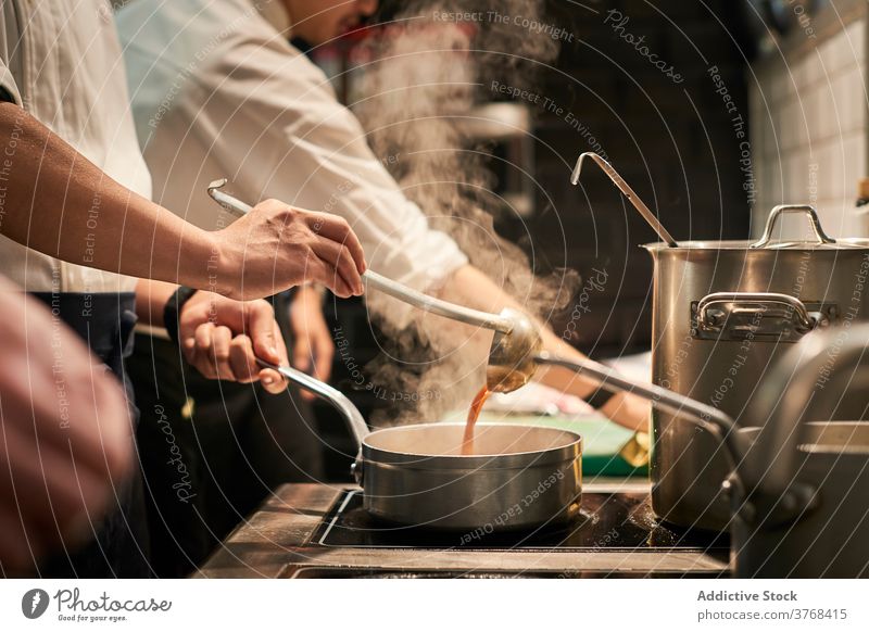 Crop chef cooking sauce in kitchen saucepan restaurant prepare delectable stove hot uniform professional job work food delicious steam cuisine staff gourmet