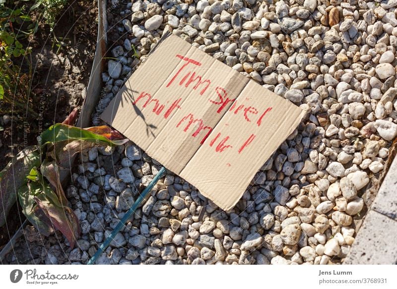 A sign saying "Tim play with me!" paperboard Red Gravel bed Plant Garden Summer playing children Ball games prohibited Playing corona Loneliness