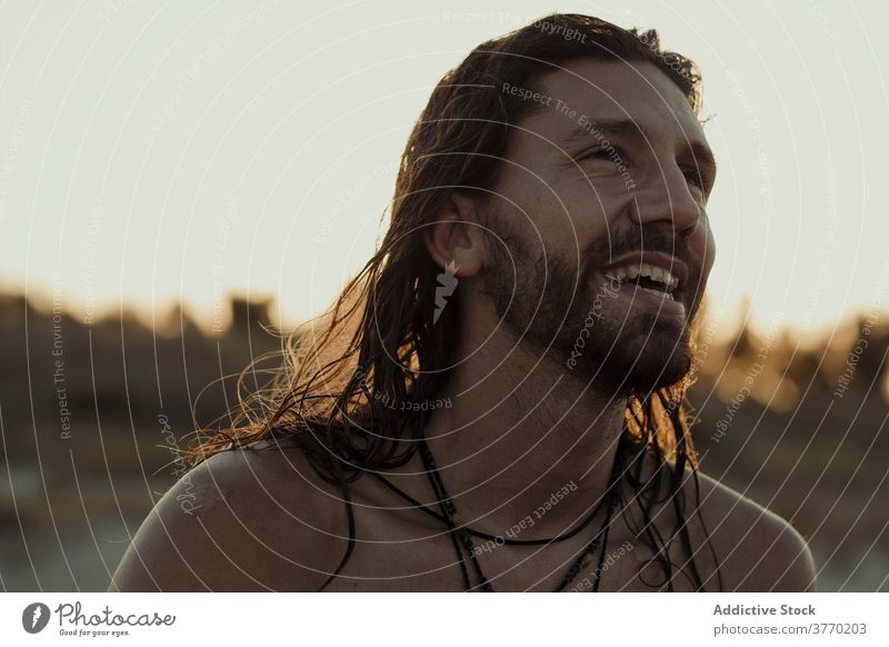 Calm man relaxing on beach at sundown sunset summer enjoy tranquil long hair carefree handsome evening male sand shore sit coast vacation naked torso shirtless