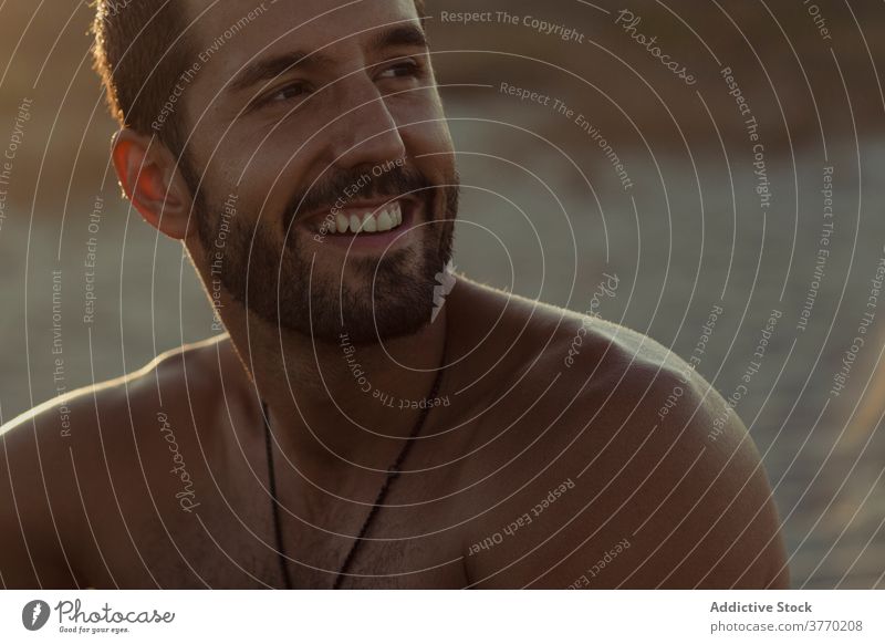 Calm man relaxing on beach at sundown sunset summer enjoy tranquil carefree handsome evening male sand shore sit coast vacation naked torso shirtless serene