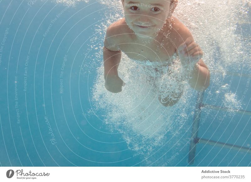 Cheerful boy in swimming pool kid dive playful delight childhood vacation summer having fun water recreation joy aqua cheerful swimsuit clear holiday pleasure