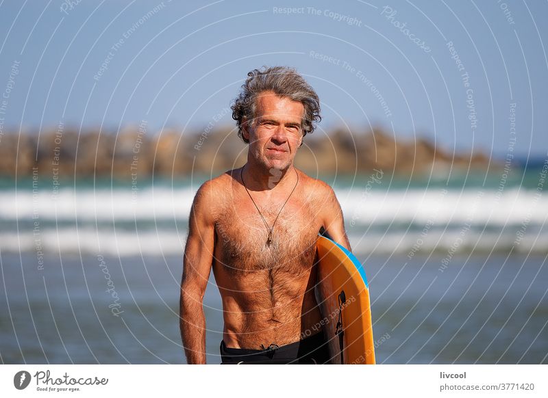 mature surfer on the beach shore, zurriola-spain senior man practicing water people adult board surfboard neoprene surfboarder lifestyle sport surfing foam