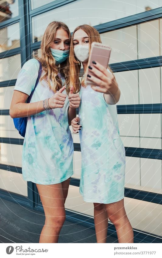 Young women girls taking selfie wearing face masks to avoid virus infection caucasian cellphone conversation covid-19 female lifestyle mobile outbreak outdoors