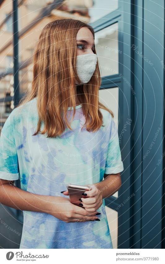 Portrait of young woman girl standing at store front downtown wearing face mask to avoid virus infection caucasian cellphone conversation covid-19 female