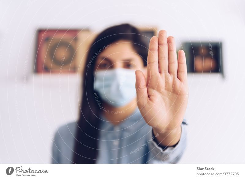 Coronavirus concept. Girl wearing a mask for protection say stop with her hands to coronavirus. Global call to stay home. covid quarantine 2019-ncov influencer