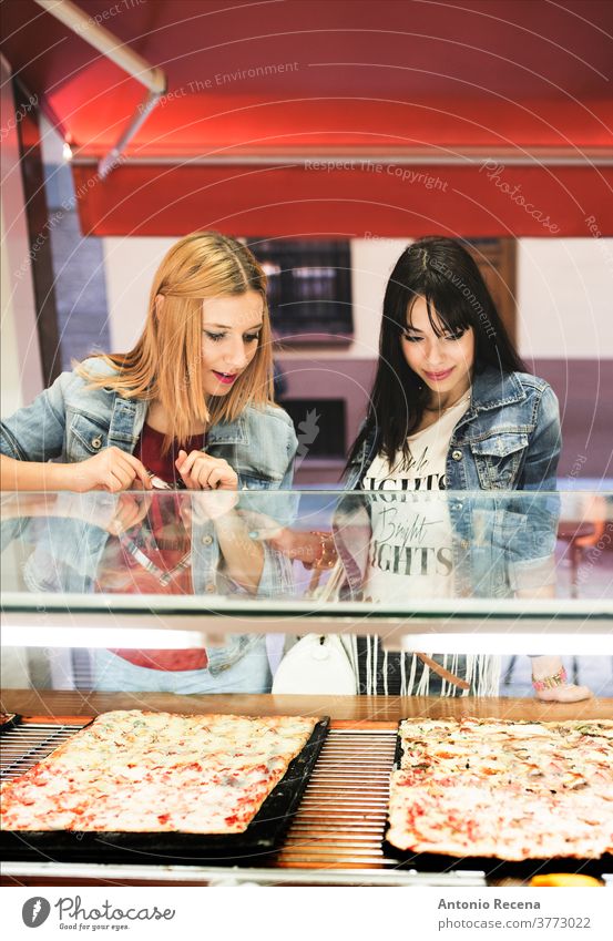 Pretty young women choosing pizza in outdoors store woman eating city food temptation meal street food fresh city life ready-to-eat cooked casual clothing