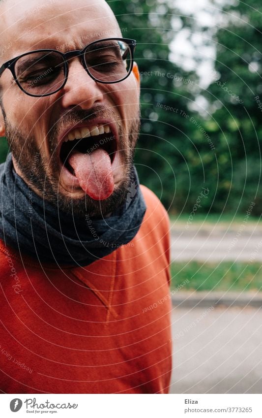 A man with glasses, beard and red sweater sticks out his tongue in disgust. Disgust stick out one's tongue disgusted bah Tongue Stick out Man Profile hate Yuck