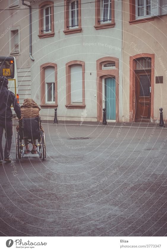 A man pushes a disabled person in a wheelchair Wheelchair handicap Mobility Health care Rainy weather Illness Trip Push walking impediment Handicapped Inclusion