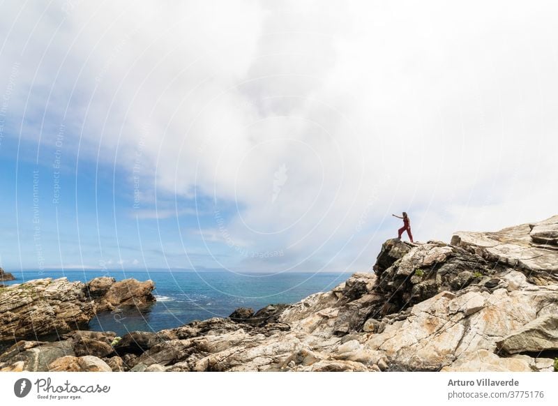 general shot of the Galician coast with a woman perched on some rocks observing the horizon sea traveler mountain freedom summer landscape sunset backpack