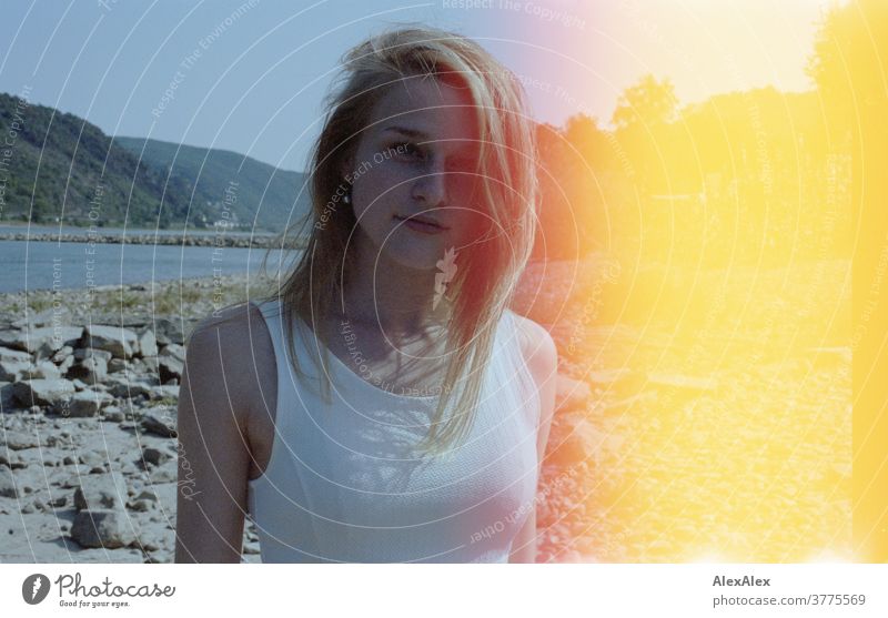 Backlit portrait of a young woman standing on a stone embankment on the banks of the Rhine - with light appearance or exposure errors and light leaks Woman