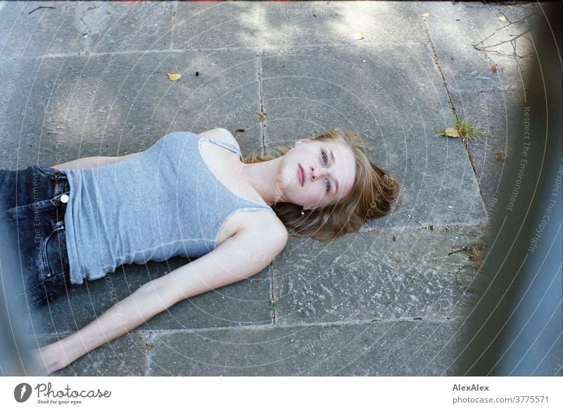 Portrait of a young woman lying on the floor and looking up through bars into the camera Woman Young woman Slim already athletic Blonde youthful 18-25 years