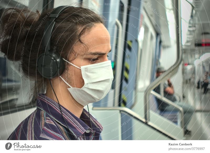 Masked sad looking teenager listening to music with headphone inside the subway metro underground mask smart phone sitting man young student millennial