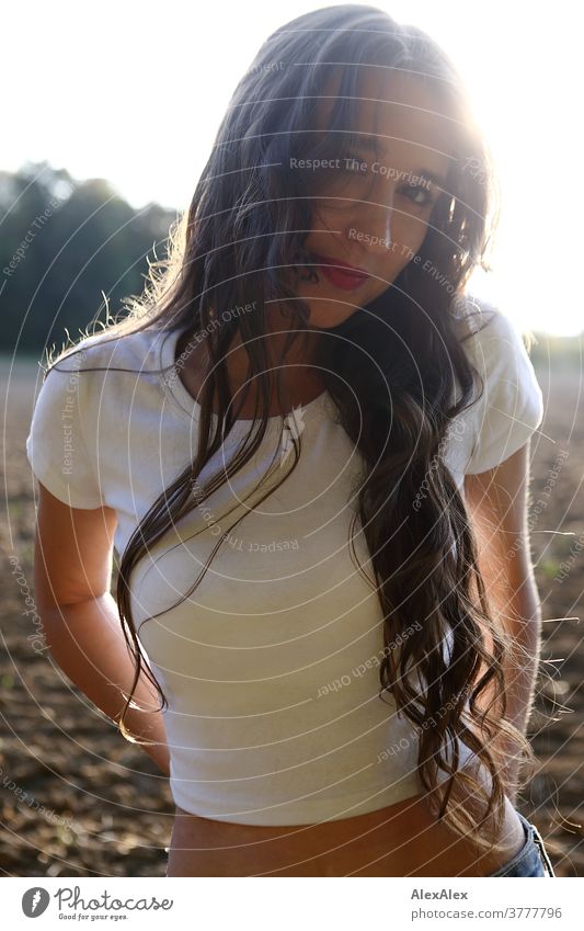 Backlit portrait of a young woman standing in front of a field and looking into the camera Woman already Near fit daintily Skin Face Blonde Direct Long-haired