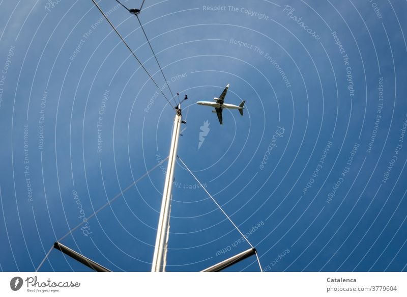 An airplane in landing approach, in the foreground a yacht mast, blue sky from the frog's perspective Airplane Airplane landing Aviation Flying