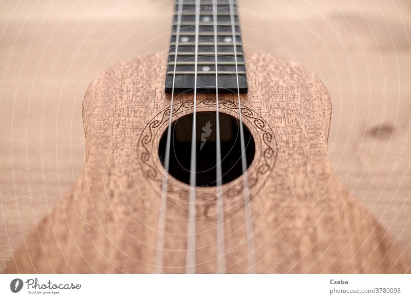 Brown ukulele on wooden background with shallow depht of field instrument acoustic musical string brown guitar rosette hawaiian object art closeup close up