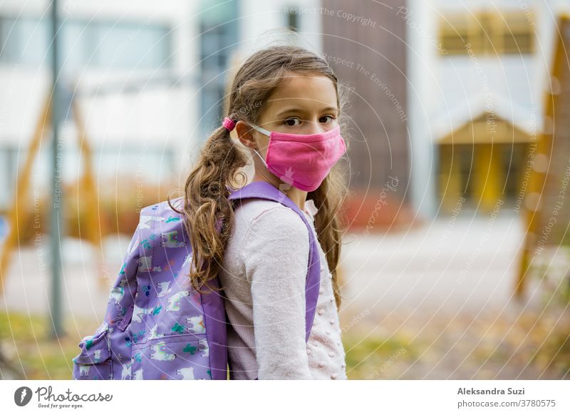 Schoolgirl wearing protective fabric reusable face mask going to school. School education during the coronavirus pandemic. Security measures and social distancing