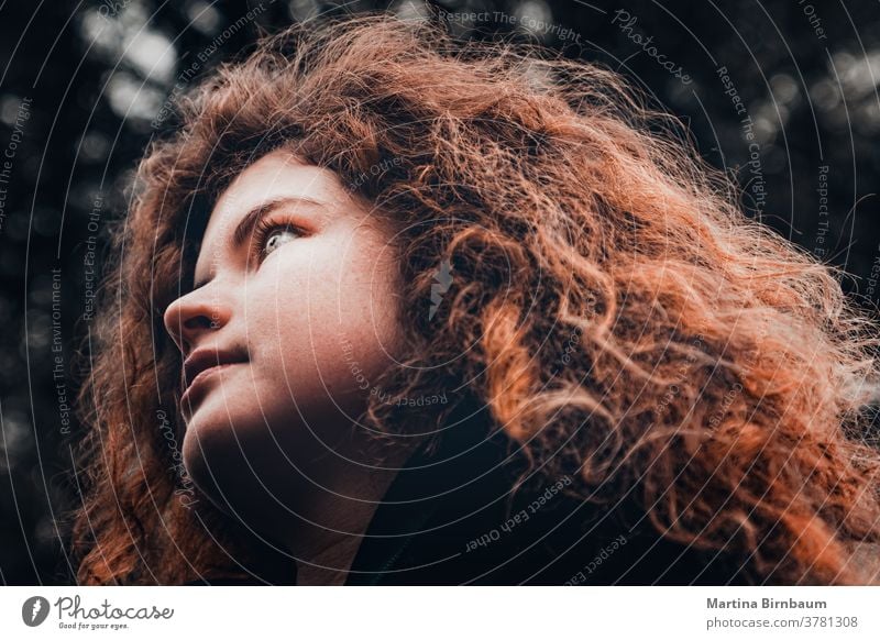 Young woman with wild red curly hair looking hopefully in the distance face girl one beautiful caucasian beauty person square hairstyle curls people vogue