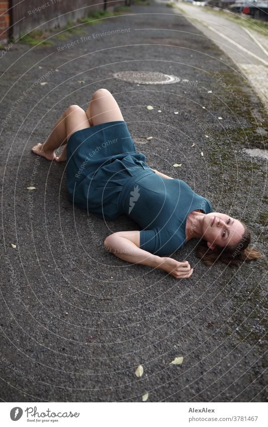 Young woman in a turquoise dress lies on a ramp and looks upside down into the camera Expectation Colour photo Looking into the camera Uniqueness Summer