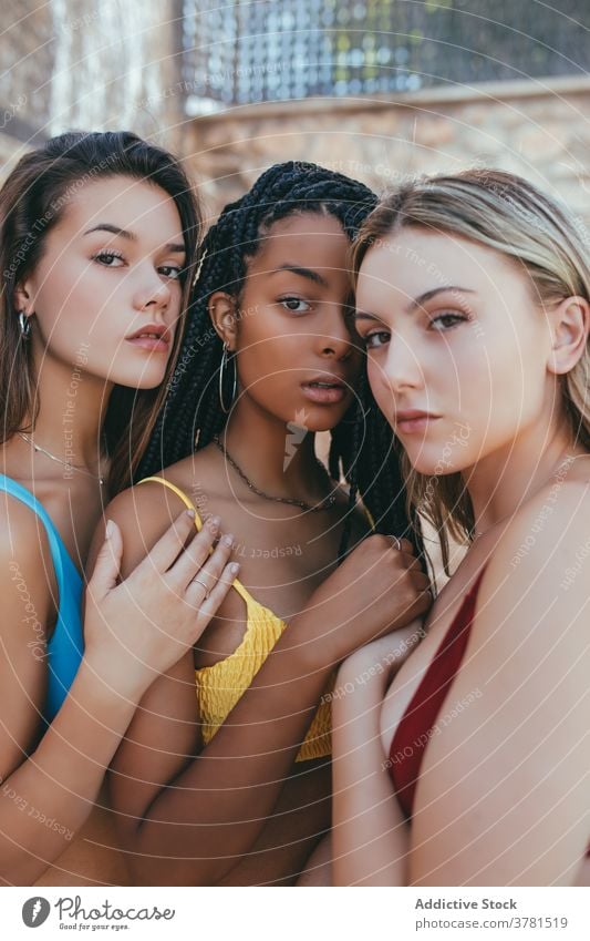 Young diverse women in bikini standing together model calm slim bra tranquil friendship unique camera multiracial multiethnic african american black cuddle hug