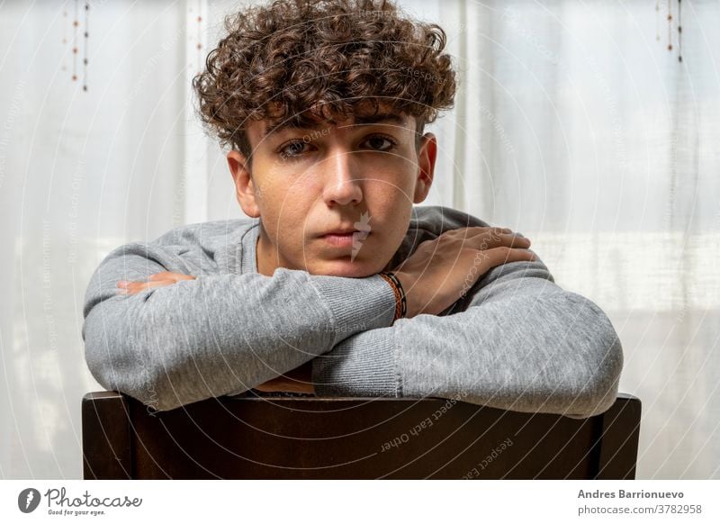 Attractive young man with curly hair wearing gray sweatshirt posing on white curtains background cheerful casual smile male adult handsome happy attractive