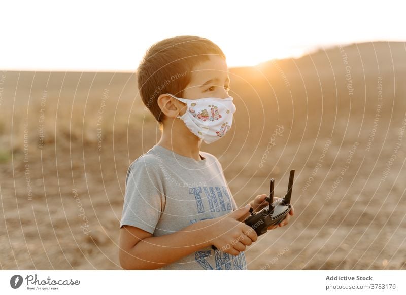 Little kid operating drone in field control remote operate using mask boy play little asian ethnic male child childhood game entertain device uav handset pilot