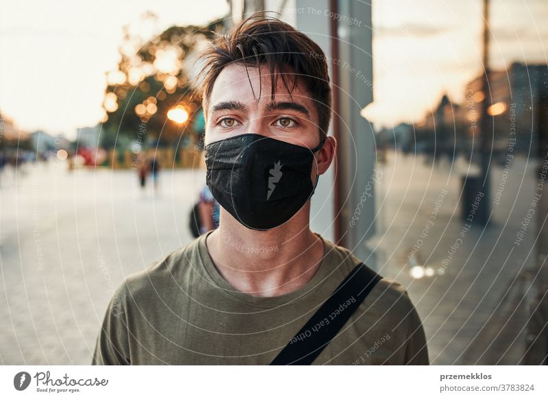 Young man walking along a store front in the city center wearing the face mask to avoid virus infection caucasian conversation covid-19 lifestyle outbreak