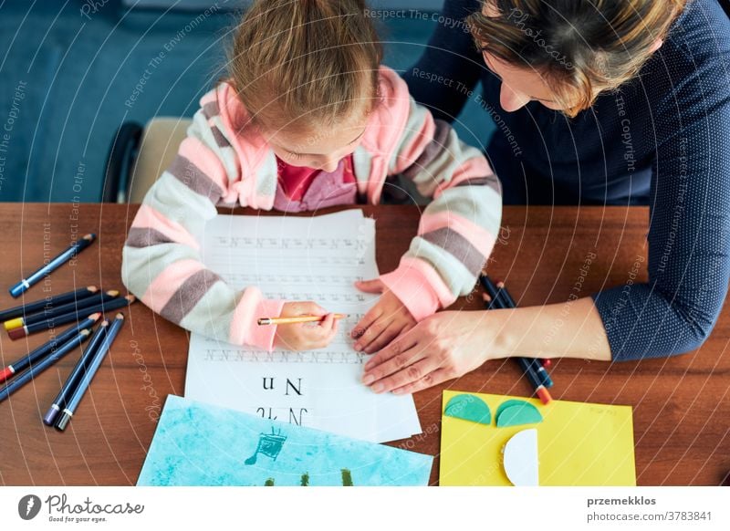 Little girl preschooler learning to write letters with help of her mother attention caucasian child childhood cute education educational fun home kid little