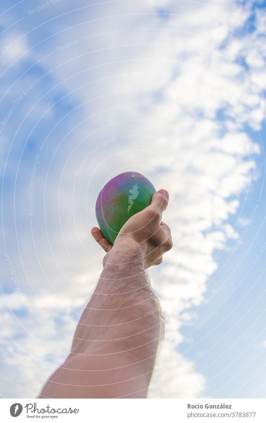 Colorful mango in a male hand with the sky as background colorful high flying ecological eco friendly tropical fruit Tropical fruits colorfull