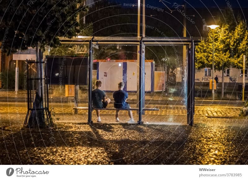 With a friend it's not bad if you have to wait long for the train Stop (public transport) Guys teenager Evening Rain Wet conceit lanterns Street Tram Bus