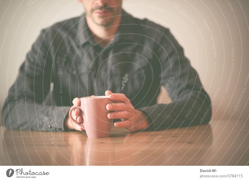 Man holds a cup in his hand and sits at the table Sit Wait Table Cup Coffee Mug hands conversation Drinking