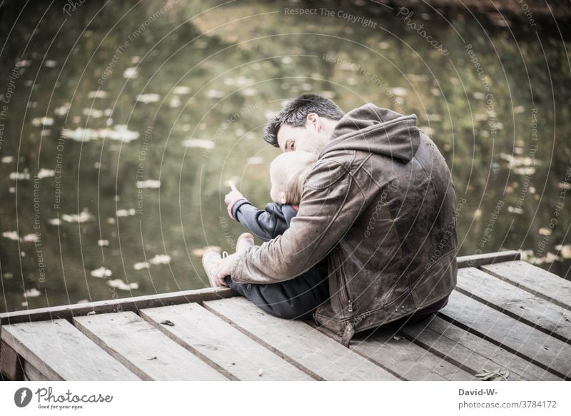 Father and child sitting together on a jetty by the lake Child Nature Footbridge Lake Sit in common at the same time Parents Love Explain Indicate Autumn