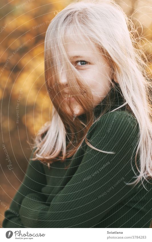 Portrait of a beautiful teenage girl with blond hair and blue eyes with a smile on her face in an autumn park happy blonde yellow portrait leaf fall season